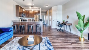 A modern kitchen with dark wood cabinets, stainless steel appliances, and a central island with bar stools. - Ayasha River-view King Bed Suite in Keystone/Broad-Ripple/Carmel (Indianapolis)