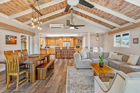 A spacious living area with a dining table, sofas, and a kitchen in the background.