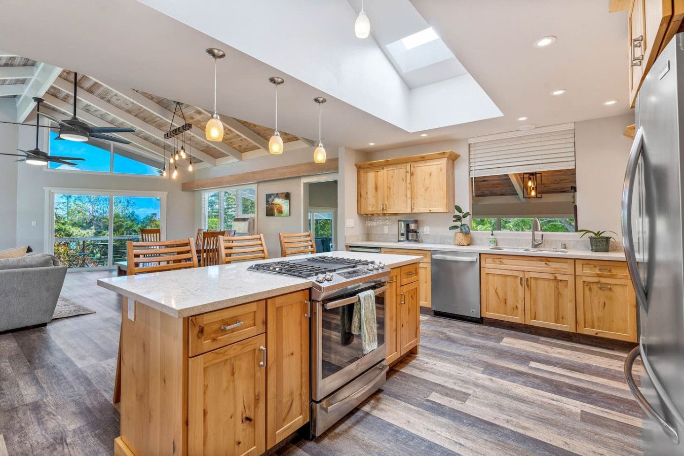 A modern kitchen with wooden cabinets, a central island, and a skylight.