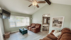 A spacious living room with a ceiling fan, a brown leather sofa, a brown recliner, and a dining area with a table and chairs. - The Bungalow on Lake Drive (Shawano)