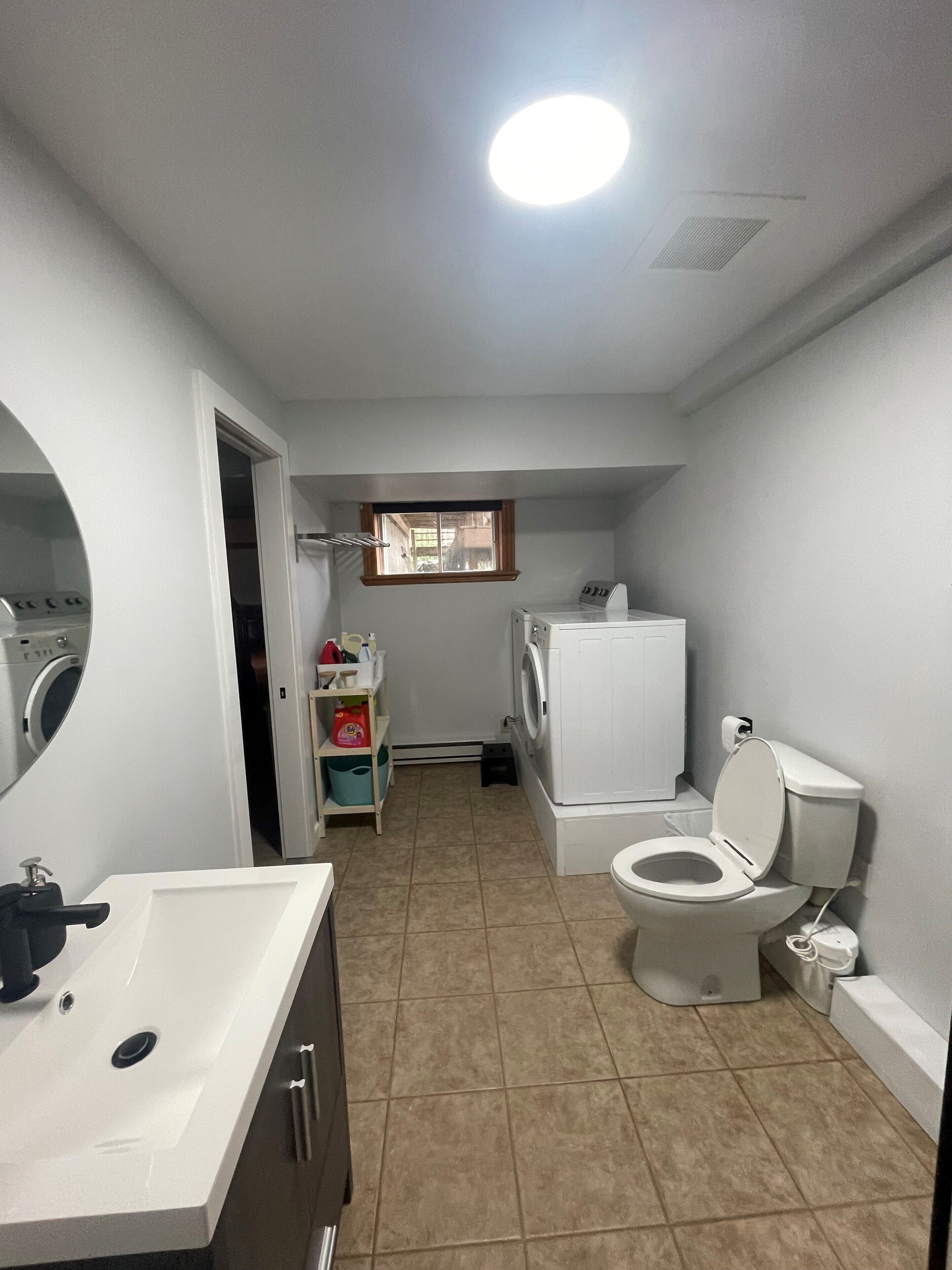A compact bathroom with a sink, toilet, and washing machine.