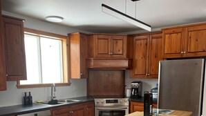 A kitchen with wooden cabinets, a stainless steel refrigerator, a wooden table, and a dishwasher.