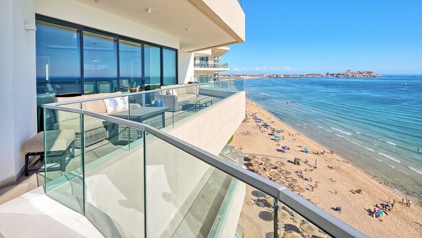 A modern hotel balcony with glass railings overlooking a beach and the sea. - LUXURY NEW OCEANFRONT CONDO- Las Palomas PH 3, 5BR/BA, 4485 Total SF , Sleeps 12 (Puerto Peñasco)