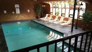 Un espace piscine doté d’une terrasse en bois, de chaises longues et offrant une vue dégagée grâce à de grandes fenêtres.