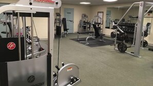 Une salle de sport équipée de divers appareils d’entraînement, notamment une machine à câbles et des supports à poids.