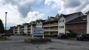Une enseigne indiquant un hôtel de style nordique devant un immeuble à plusieurs étages, doté de balcons et d’un espace de stationnement.