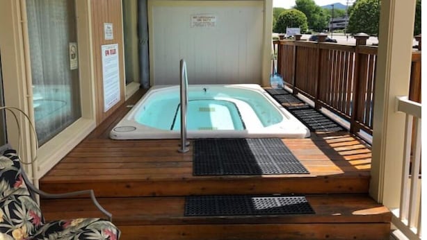 Un bain à remous sur une terrasse en bois, avec une clôture en bois et un espace abrité.