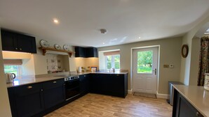 Una cocina moderna con gabinetes negros, suelo de madera en espiga y una isla grande.