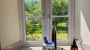 Una cocina con ventana, un lavamanos y una botella de jabón Bower.