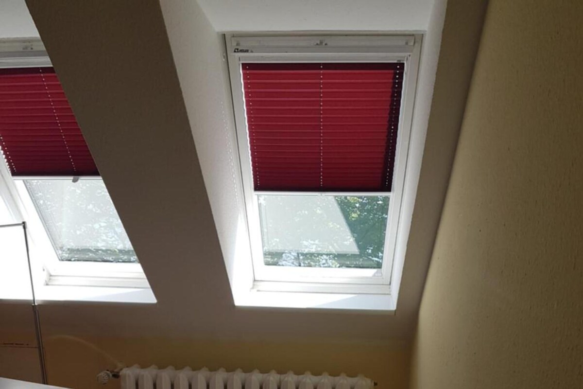 Ein kleines Zimmer mit einem Einzelbett, einem Oberlicht und einer Heizung.