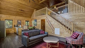 A wooden cabin interior with a living room, kitchen, and a wooden staircase. - *Cozy 2BR + LOFT! • Game Room • HOT TUB! • Arcade* (Sevierville)