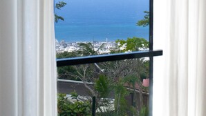A window with a view of the ocean and a cityscape. - L'Escapade Bellepierre (Saint-Denis)