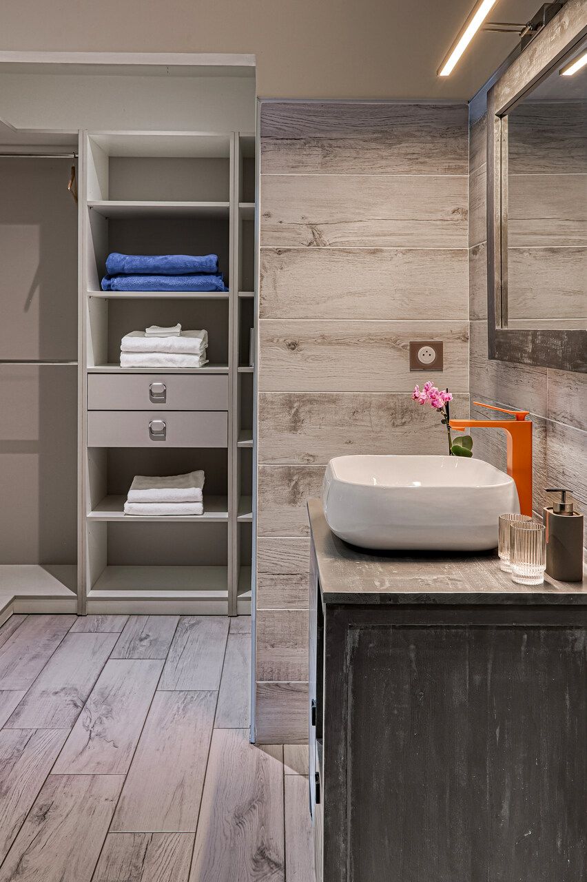 A bathroom with a built-in shelf unit, a sink with a modern faucet, and a mirror above it.