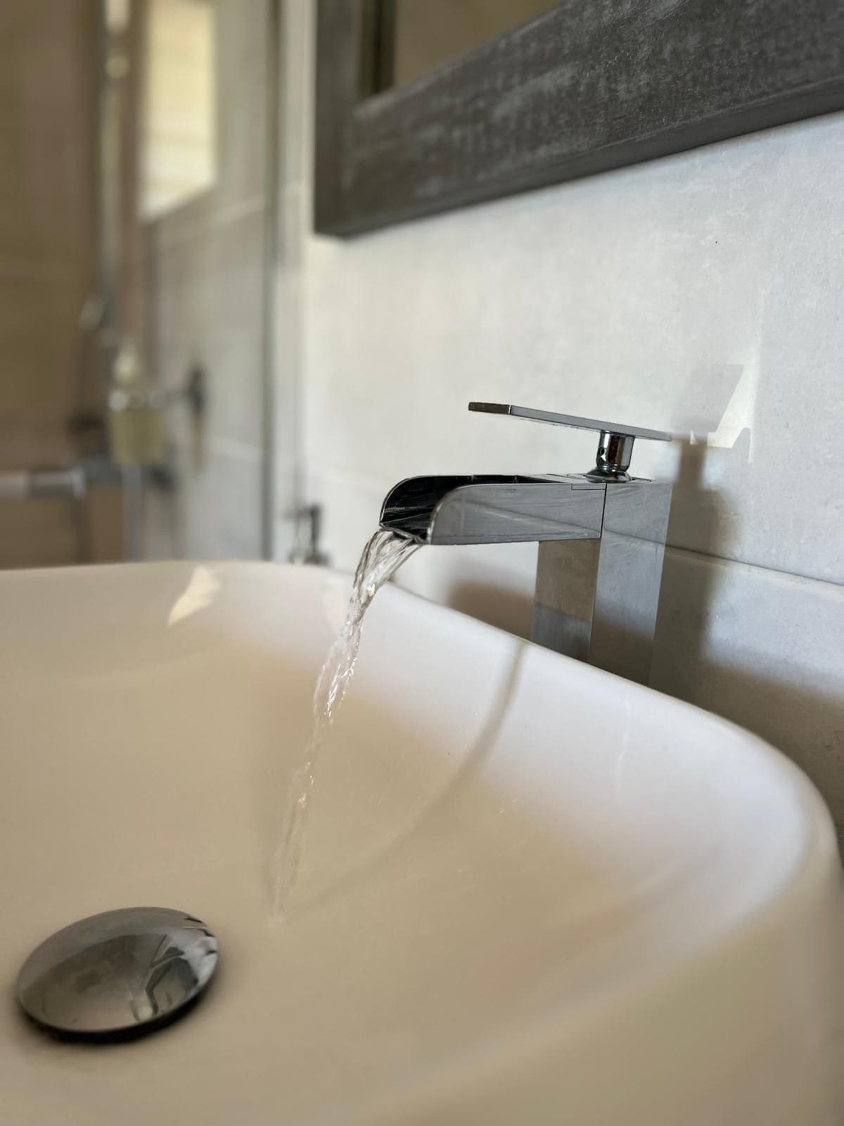 A bathroom sink with running water, a chrome faucet, and a mirror on the wall.