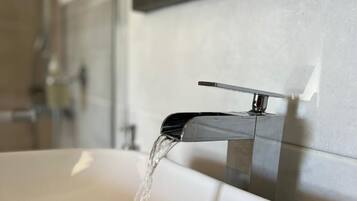A bathroom sink with running water, a chrome faucet, and a mirror on the wall.