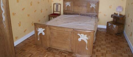 Un dormitorio con una cama de madera, una mesita de noche, un aparador y papel tapiz estampado.