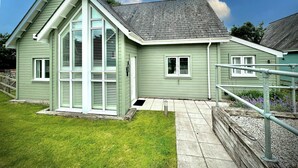 A single-story house with a gabled roof, a front porch, and a small front yard. - Trewhiddle Villa 13 (St Austell)