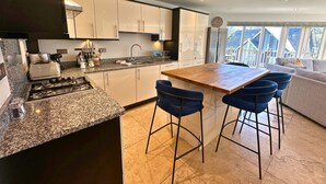 Een moderne keuken met granieten aanrechtbladen, roestvrijstalen apparatuur en een centraal eiland met barkrukken.