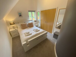 Quarto com cama grande, mesas de cabeceira, guarda-roupa e espelho.