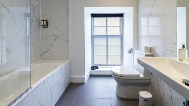 A modern bathroom with a glass-enclosed shower, a toilet, and a sink with a marble countertop. - Seaforth (Isle of Lewis)