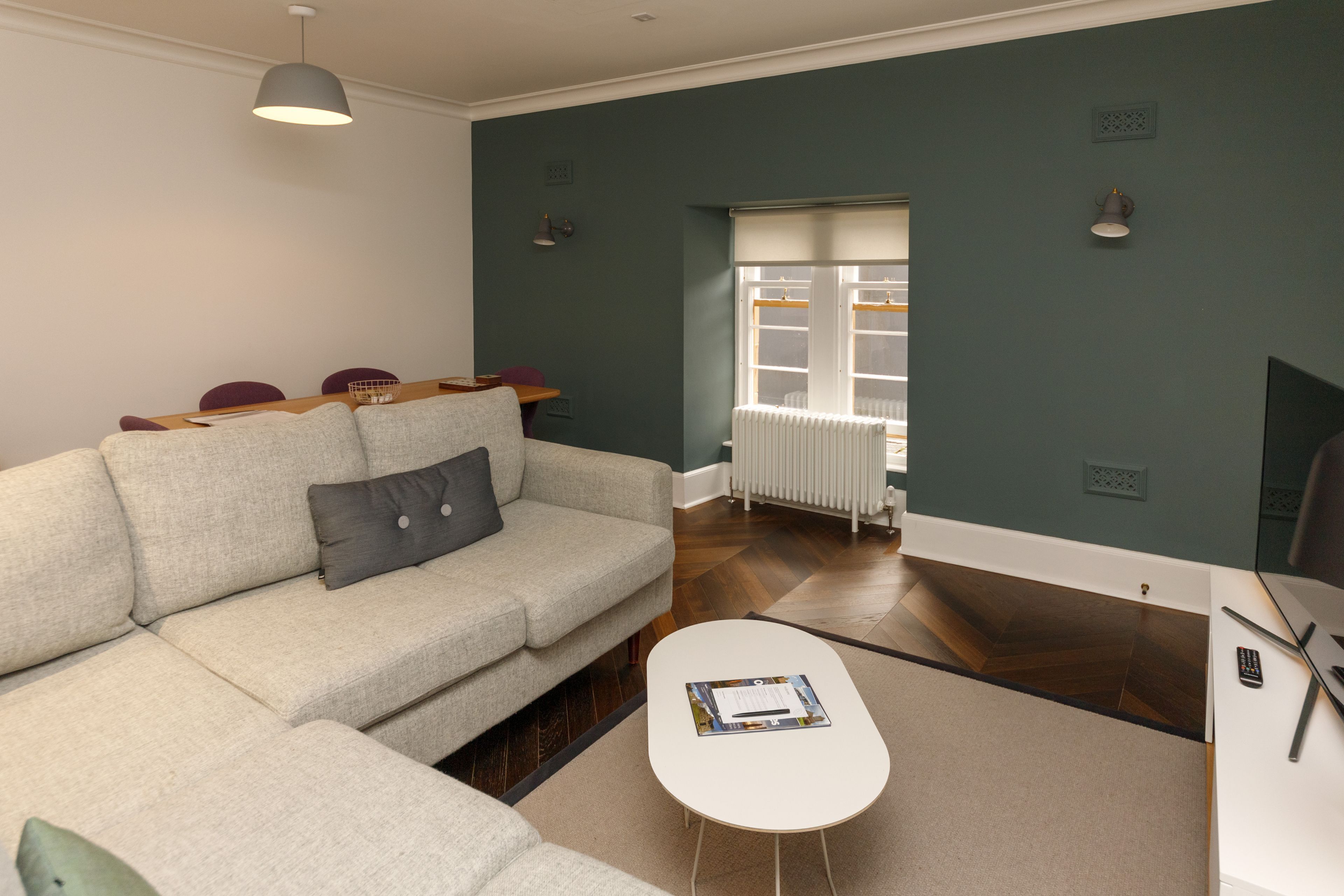 A modern living room with a sofa, a coffee table, and a dining area with chairs and a table.