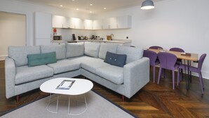 A modern living room with a grey sectional sofa, a white coffee table, and a dining area with purple chairs and a wooden table. - Seaforth (Isle of Lewis)