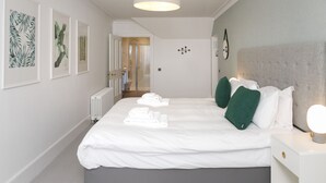 A modern hotel room with a large bed, a bedside table with a lamp, and framed artwork on the walls. - Seaforth (Isle of Lewis)