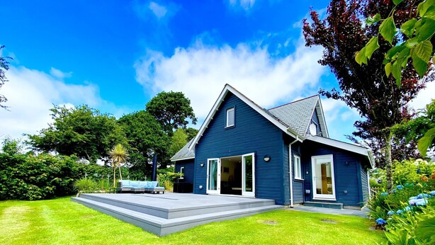 Een modern huis met twee verdiepingen, een ruime voortuin, een overdekte patio en een garage.