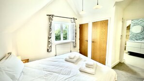 Een slaapkamer met een groot bed, een raam met gordijnen, een radiator en een houten deur.