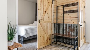 Een slaapkamer met een houten deur, een bed, een tafeltje en een bloempot.