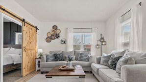 Een woonkamer met een bank, salontafel en een schuifdeur in boerderijstijl.