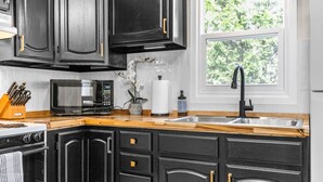 Een moderne keuken met donkere kastjes, een houten aanrecht, een roestvrijstalen spoelbak, een magnetron en een oven.