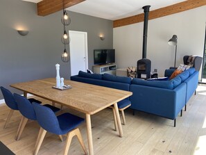 Ein modernes Wohnzimmer mit einem Holzesstisch, blauen Sofas und einem eingebauten Kaminofen.