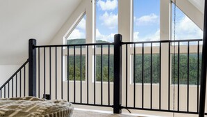 A high-ceilinged room with a black metal railing, large windows, and a ceiling fan. - Alpine Escape: Family-Friendly Cabin with Spectacular Views (Divide)