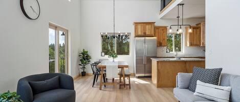 Una cocina moderna con armarios de madera, un refrigerador de acero inoxidable y un comedor con mesa y sillas.