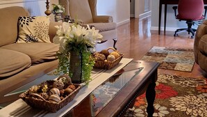 Un salon comprenant un canapé, une table basse agrémentée d’objets décoratifs, une horloge et un ventilateur de plafond.