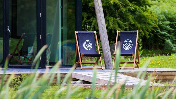 Two wooden chairs with a leaf logo on a wooden deck. - Yorkshire Dales Lodge 4 Family (Richmond)