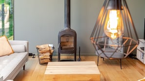 A cozy living room with a wood-burning stove, a comfortable sofa, a wooden table, and a hanging light fixture. - Yorkshire Dales Lodge 4 Family (Richmond)