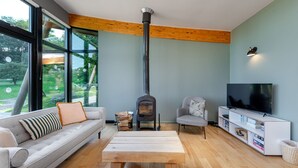 A living room with a large window, a fireplace, a sofa, a TV, and a wooden coffee table. - Yorkshire Dales Lodge 4 Family (Richmond)