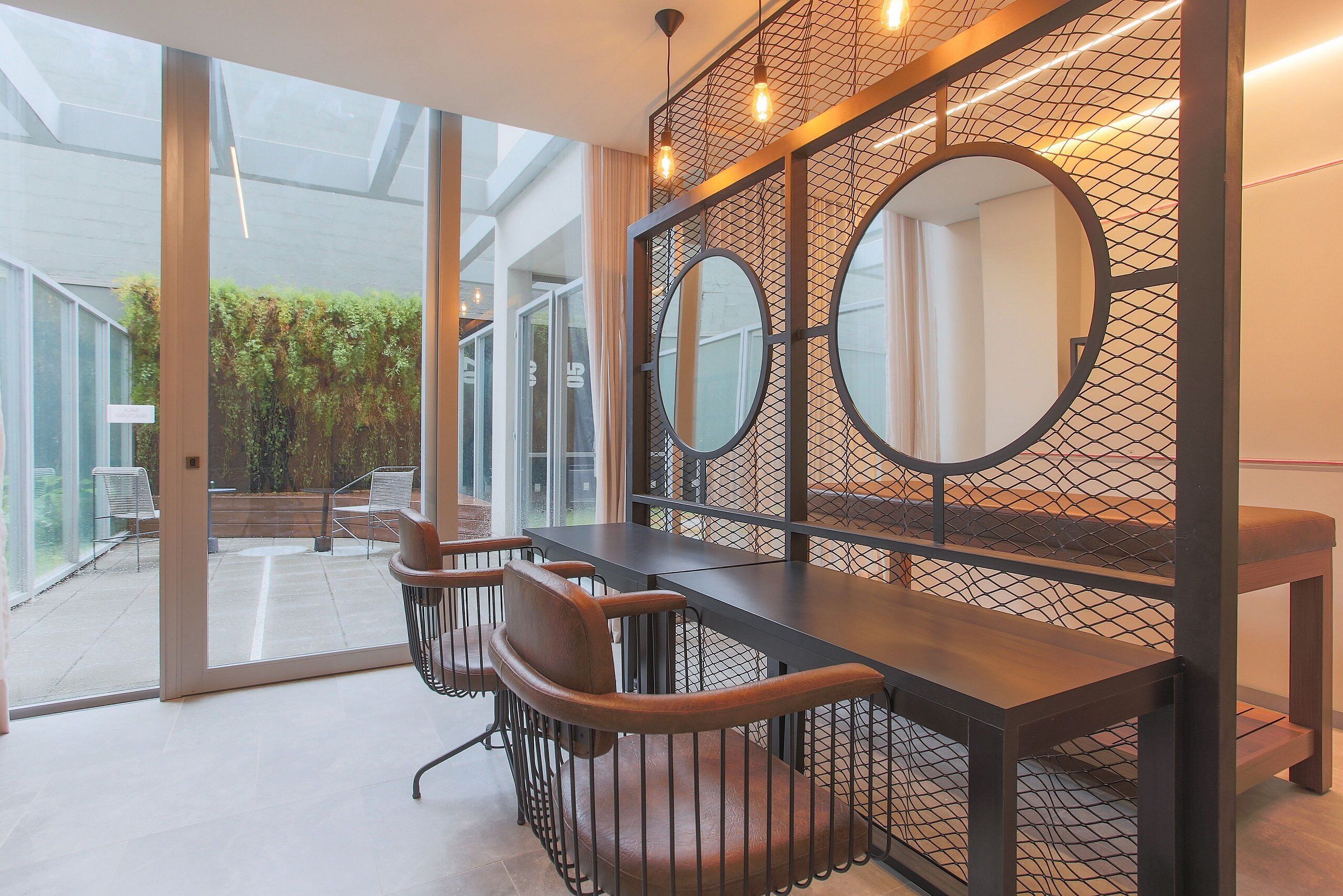 A modern interior with a glass door leading to an outdoor area, a wooden table with chairs, and a decorative wall with circular mirrors.