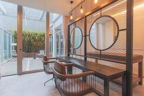 A modern interior with a glass door leading to an outdoor area, a wooden table with chairs, and a decorative wall with circular mirrors.