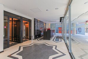 A modern hotel lobby with glass doors, a reception desk, and a patterned floor. - On Imarés (São Paulo)
