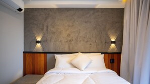 Een moderne hotelkamer met een bed, een bankje en een gestructureerde muur.