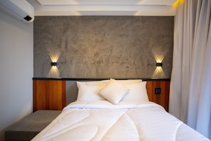 A modern hotel room with a bed, a bench, and a textured wall. - On Imarés (São Paulo)
