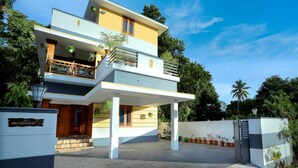 A modern two-story house with a balcony, a covered porch, and a gated entrance. - Oyster Marris Homestays in Trivandrum (Thiruvananthapuram)