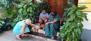 Three people sitting on steps surrounded by lush green plants. - Oyster Marris Homestays in Trivandrum (Thiruvananthapuram)