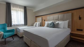 Una camera d'albergo con un letto grande, un comodino, una sedia e una finestra con tende.