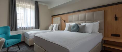 A hotel room with a large bed, a bedside table, a chair, and a window with curtains.