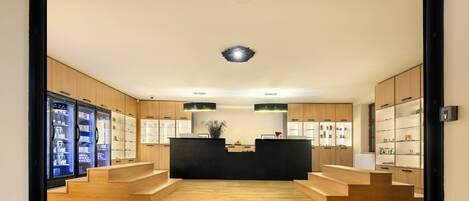 Una recepción moderna con un mostrador central, suelo de madera y vitrinas de cristal.