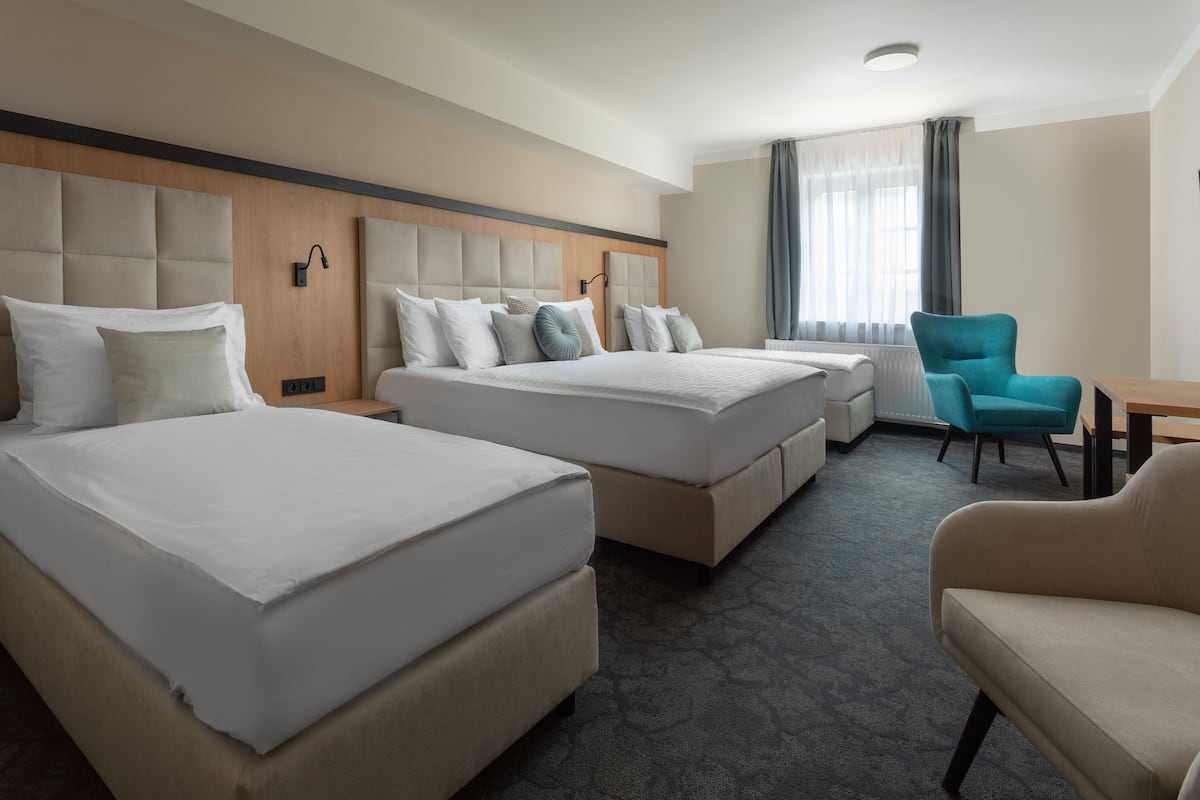 A hotel room with two beds, a desk, and a chair.